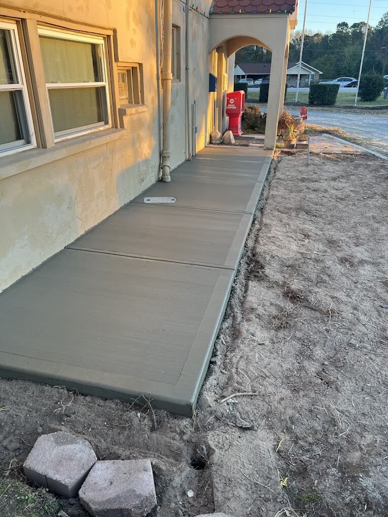 Freshly finished concrete sidewalk with clean control joints along a building