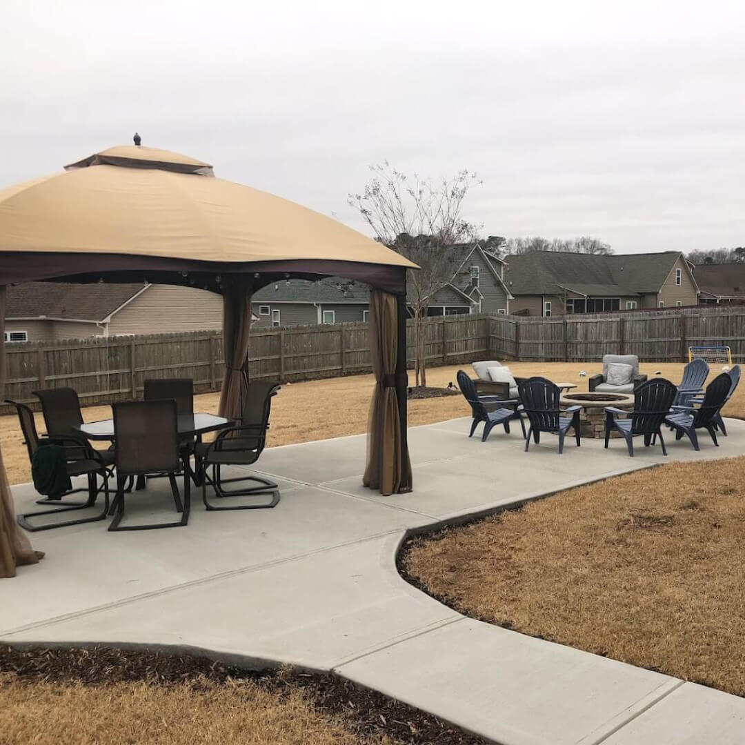Outdoor patio with brick firepit and lounge chairs in a backyard